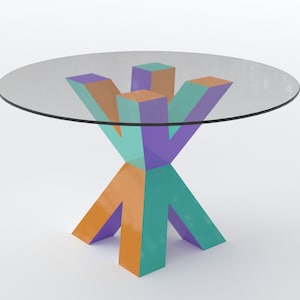 Op de afbeelding: Ronde tafel met glazen blad en geometrisch onderstel. Het onderstel heeft een stervormig ontwerp met oranje, turquoise en paarse blokken. De tafel is een modern ontwerp, geschikt voor een woon- of eetkamer. De hoogte is ongeveer 75 cm.