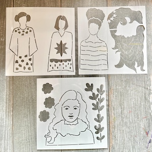 May include: Four white stencils with cutout designs. The stencils feature female figures and floral elements. One stencil depicts a woman in a dress with a dotted pattern. Another shows a woman with a star design. The other two stencils show women with curly hair and floral elements.