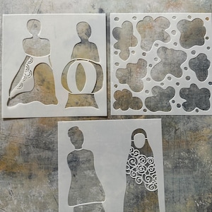 May include: Three white square stencils featuring cut-out designs. The top left stencil shows two stylized figures, one with a patterned skirt. The top right stencil displays organic cloud-like shapes and dots. The bottom stencil depicts two figures.