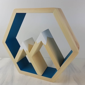 May include: A hexagonal wooden shelf with a blue interior and a mountain range design. The mountains are made of wood and painted white and beige.
