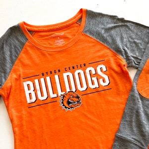 May include: Orange and gray long-sleeve shirt with the words "Byron Center Bulldogs" and a bulldog mascot graphic.
