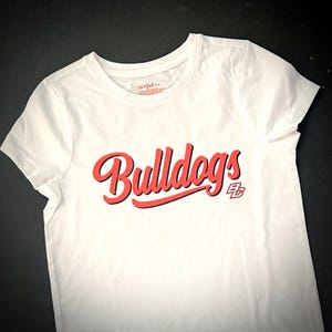 May include: White t-shirt with a red "Bulldogs" graphic and a red "B.C." logo.