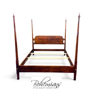 May include: A dark brown wooden four-poster bed frame featuring tall, slender posts with pointed finials at the top. The headboard has a curved, solid wood panel design, and the frame includes light-colored wooden slats for mattress support.