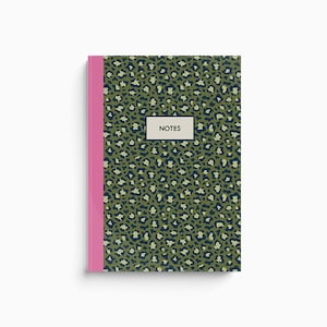 Op de afbeelding: Een notitieboek met een groene en blauwe luipaardprint en een roze rug. De voorkant heeft het woord "NOTES" gedrukt in een wit rechthoek.