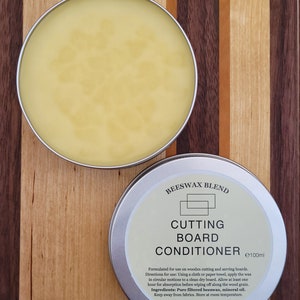 May include: A silver tin of beeswax blend cutting board conditioner with a yellow wax inside. The tin is labelled "Beeswax Blend Cutting Board Conditioner e100ml". The label also includes instructions for use and ingredients: Pure filtered beeswax, mineral oil. Made in Ireland.