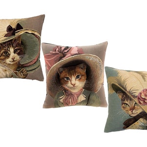 May include: Three decorative throw pillows featuring a cat wearing a hat. The pillows are made of a tapestry fabric with a vintage look. The cats are wearing different hats with feathers, ribbons, and flowers.