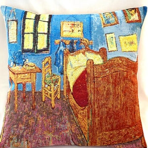 May include: A tapestry pillow featuring a painting of a bedroom with a wooden bed, a chair, and a small table. The walls are blue and the floor is a dark brown. The painting is in a style reminiscent of Vincent van Gogh.