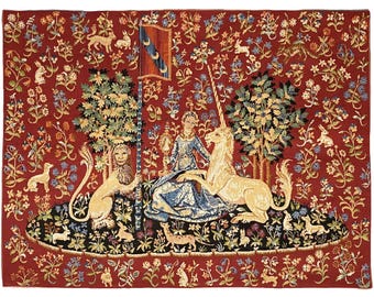 May include: A tapestry depicting a woman in a blue dress sitting with a unicorn and a lion in a lush garden setting. The tapestry is filled with intricate details, including flowers, leaves, and small animals.