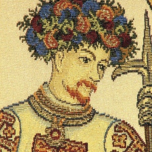 May include: Close-up of a tapestry depicting a man wearing a crown of leaves and flowers. He is wearing a tunic with a cross on the front. The tapestry is made of woven threads in shades of brown, gold, red, blue, and green.