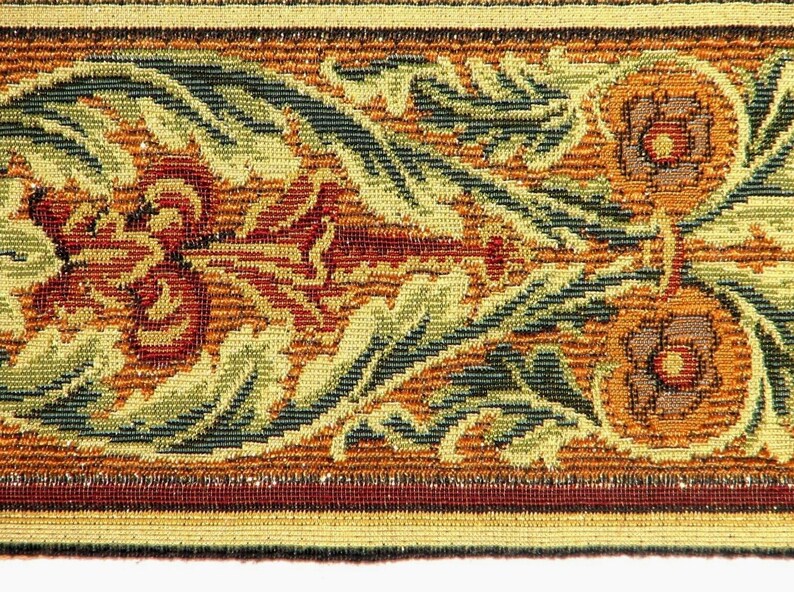 May include: A close-up of a woven fabric with a floral pattern in shades of brown, green, and red. The fabric has a textured surface and a repeating pattern of stylised flowers and leaves.