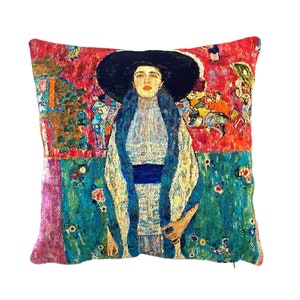 May include: A colorful tapestry pillow featuring a woman in a blue dress and a black hat. The background is a vibrant red with floral patterns.