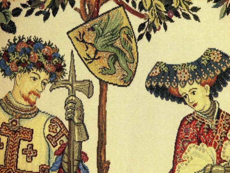 May include: A tapestry featuring a knight in armour holding a sword and a woman wearing a large, ornate hat. The knight is wearing a wreath of flowers on his head and the woman is wearing a red and gold dress. The tapestry is woven with intricate details and features a green dragon on a shield.