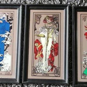 Può includere: Un set di quattro specchi da parete rettangolari con cornici nere, ognuno raffigurante l'illustrazione stilizzata di una donna in abito lungo. Le figure sono colorate in rosso, blu, bianco e verde, con dettagli floreali e linee sottili.