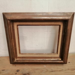 Puede incluir: Un marco de madera marrón con un borde dorado. El marco tiene un diseño sencillo y está listo para mostrar una foto o una obra de arte.