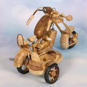 May include: A wooden motorcycle with a sidecar, both crafted from natural wood with intricate details. The motorcycle has a single front wheel and the sidecar has two wheels. The motorcycle is painted in a natural wood colour.