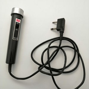 Op de afbeelding: Een zwarte microfoon met een zilveren bovenkant en een aan/uit-schakelaar. De microfoon is verbonden met een zwart snoer met een tweepunts stekker.