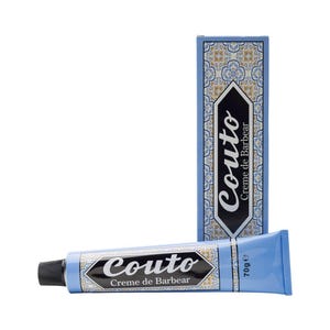 Puede incluir: Un tubo azul de crema de afeitar Couto Creme de Barbear con tapón negro y una caja a juego. El embalaje presenta el logotipo Couto en blanco y negro y un patrón decorativo azul y blanco.