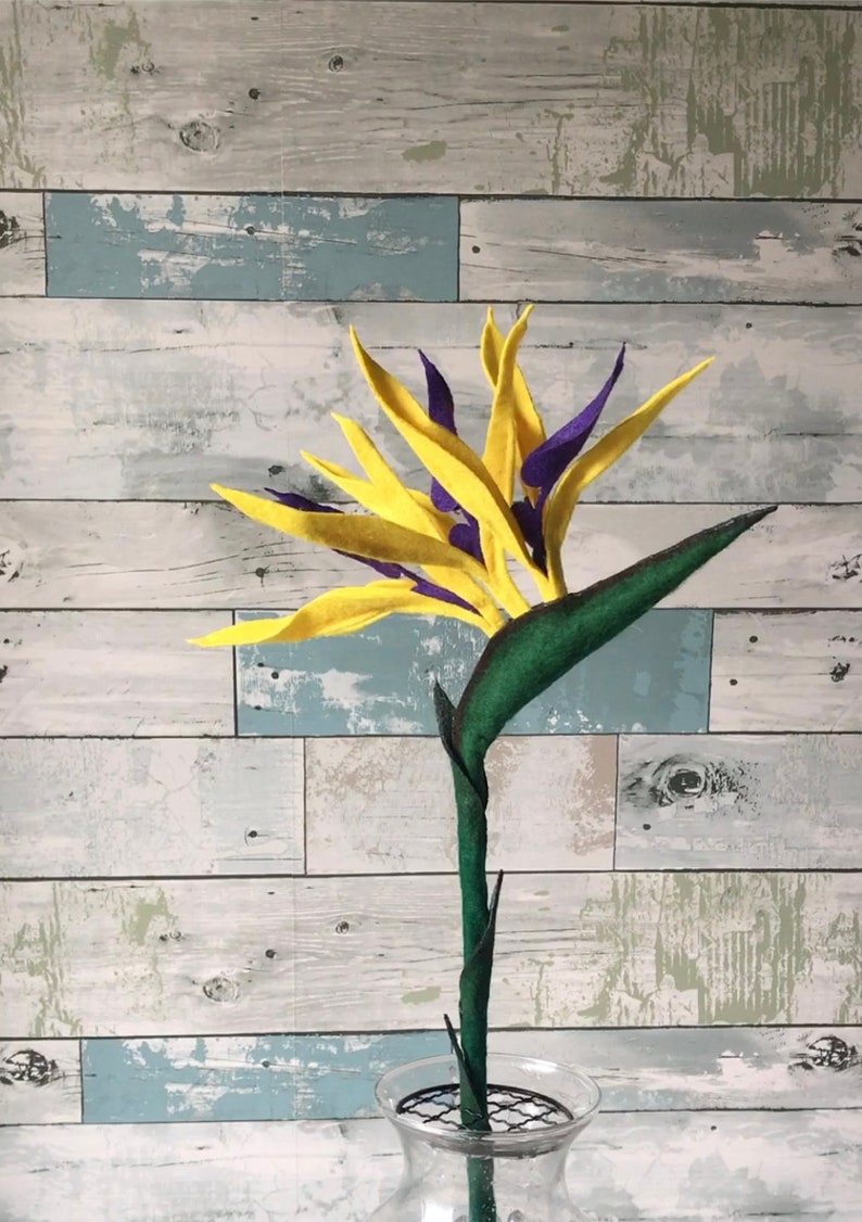 Bird of Paradise felt flower with a 15 inch; flower stem. Flower has 3 full blooms with yellow tepals and purple petals.