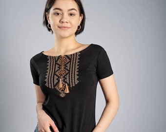 May include: A black short-sleeved t-shirt with a brown embroidered design on the front. The design features geometric patterns and tassels.