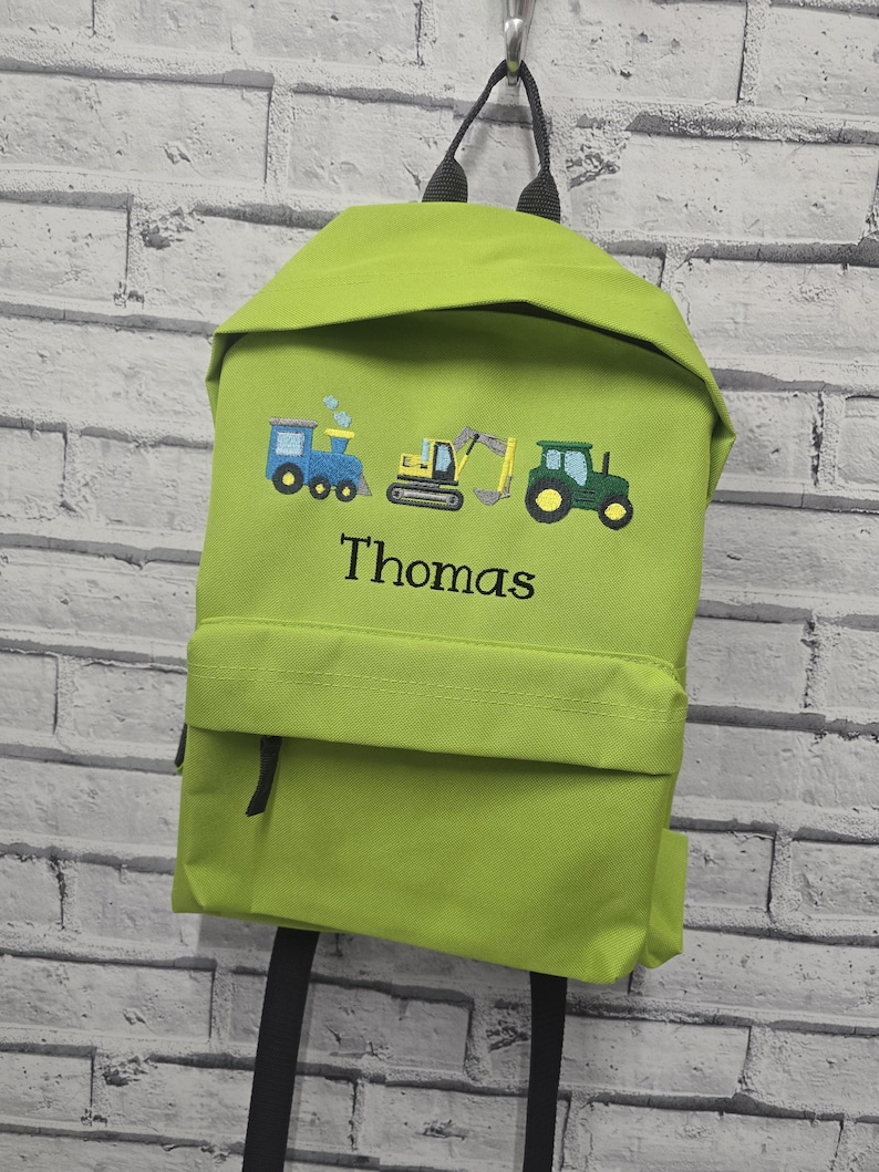 May include: Lime green backpack with embroidered images of a blue train, yellow excavator, and green tractor. The name "Thomas" is embroidered below the images. The backpack has black straps and a front pocket.