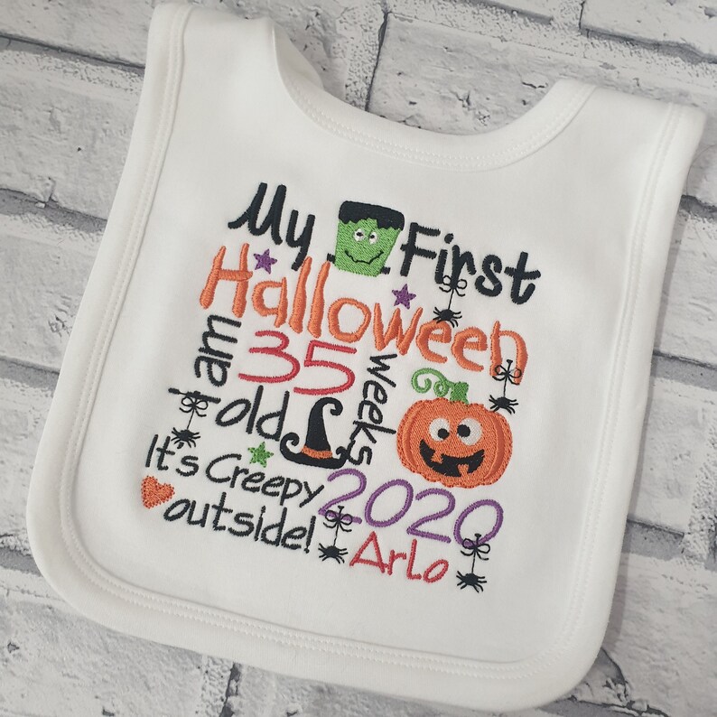 May include: White baby bib with colorful embroidered text that reads "My First Halloween I am 35 weeks old It's Creepy outside! 2020 Arlo" with a pumpkin, witch hat, spider, and Frankenstein graphic.