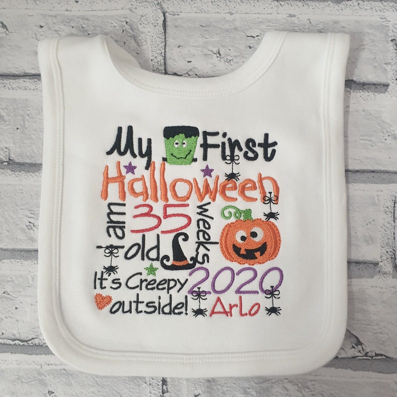 May include: White baby bib with embroidered text that reads "My First Halloween I am 35 weeks old It's Creepy outside! 2020 Arlo" with a pumpkin, witch hat, spider, and monster graphic.