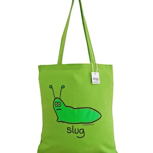 May include: A green tote bag with a cartoon slug illustration and the word "slug" printed on it. The bag has a white tag with the text "digg design" on it.
