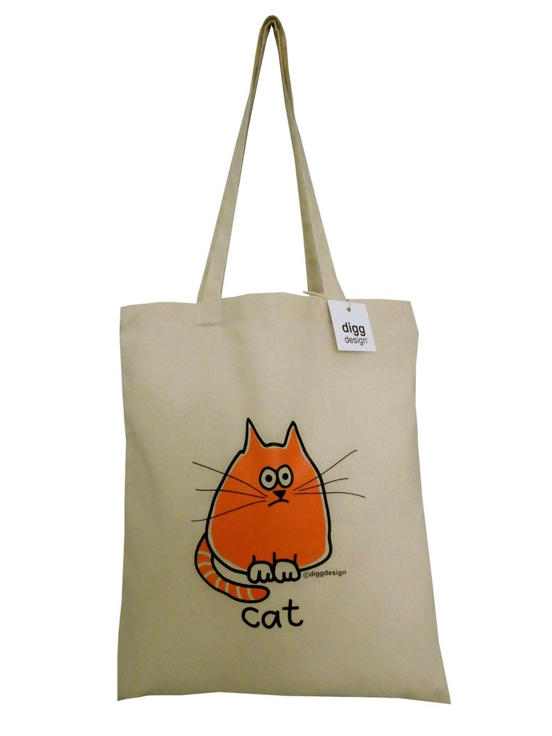 May include: A beige canvas tote bag with orange cat illustration and the text "digg design" and "cat".