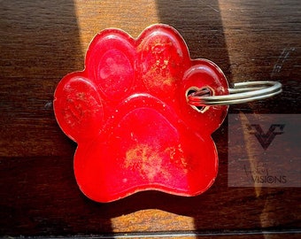 May include: Red paw print keychain with a gold heart and a silver key ring.