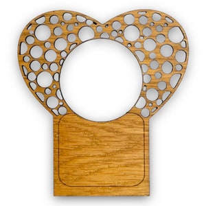 Może przedstawiać: Drewniana ramka w kształcie serca z wyciętym wzorem kół. Ramka ma prostokątny spód.