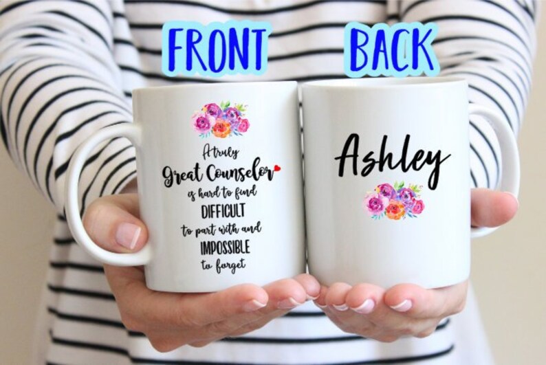May include: Two white coffee mugs with black text and floral designs. The front mug reads "A truly Great Counselor is hard to find, Difficult to part with and Impossible to forget". The back mug reads "Ashley".