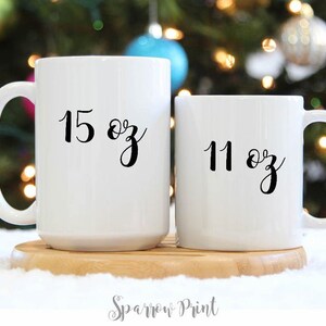 May include: Two white ceramic mugs with black lettering. The larger mug is 15 oz and the smaller mug is 11 oz.