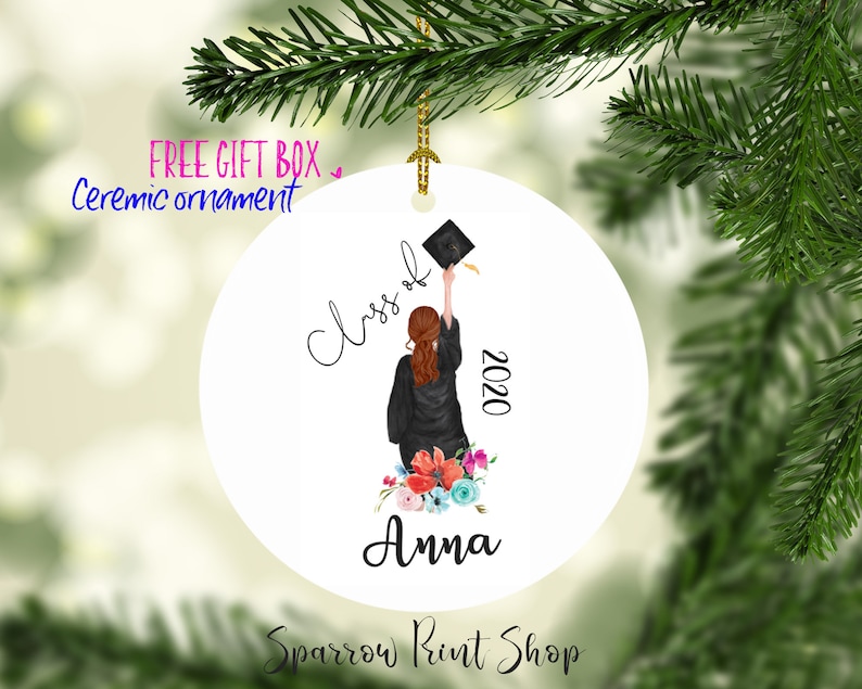 May include: White ceramic ornament with a watercolor illustration of a graduate throwing their cap in the air. The text "Class of 2020" and the name "Anna" are written on the ornament.