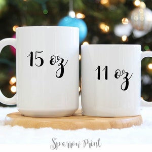 May include: Two white ceramic mugs with black lettering. The larger mug is 15 oz and the smaller mug is 11 oz.