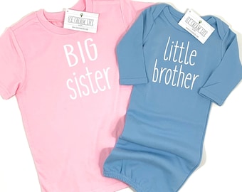 May include: Pink and blue baby clothes with the text "Big sister" and "little brother" on them.