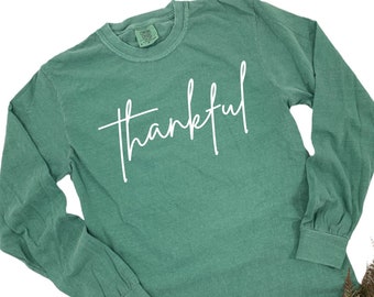 May include: A long-sleeved, green t-shirt with the word "thankful" written in white cursive script.