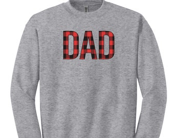 May include: A heather gray sweatshirt with the word "DAD" in large, bold, red and black buffalo plaid letters across the chest. The sweatshirt has a crew neck and long sleeves.