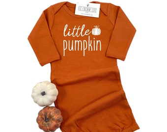 May include: Orange long-sleeved baby gown with a white pumpkin graphic and the text "little pumpkin".