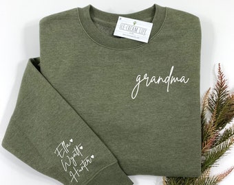 Könnte beinhalten: Ein grüner Pullover mit dem Wort "Oma" auf der Vorderseite und den Namen "Ella", "Wyatt" und "Hunter" auf dem Ärmel gestickt.