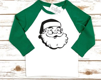 May include: White and green raglan-style shirt featuring a black and white Santa Claus graphic. The shirt has green sleeves and a white body. The tag reads "ICE CREAM LIFE".