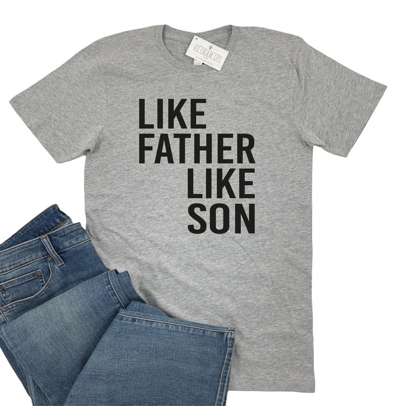 May include: A gray t-shirt with the text "Like Father Like Son" printed in black.