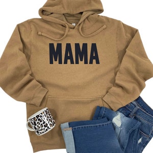 May include: A brown hooded sweatshirt with the word "MAMA" printed in black on the front.