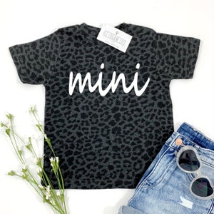 May include: A black and grey leopard print t-shirt with the word "mini" in white text.