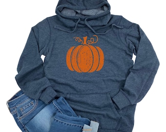 May include: A navy blue hooded sweatshirt with a large orange pumpkin graphic on the front. The sweatshirt has a kangaroo pocket and is paired with a pair of blue jeans.