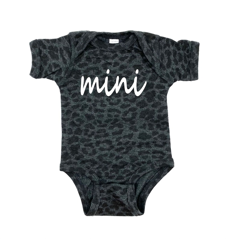 May include: A black and gray bodysuit with a leopard print pattern. The bodysuit has short sleeves and a white inscription that says "mini".