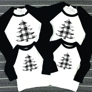 K&ouml;nnte beinhalten: Vier schwarze und wei&szlig;e Baseball-Shirts mit einem schwarzen und wei&szlig;en karierten Weihnachtsbaum-Design. Die Shirts haben wei&szlig;e &Auml;rmel und einen schwarzen Kragen.