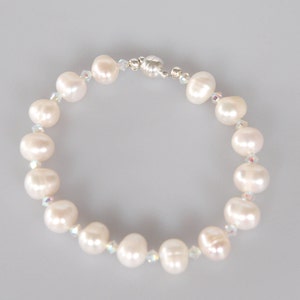 May include: A white pearl bracelet with a silver clasp. The bracelet is made with small white pearls and clear crystals.