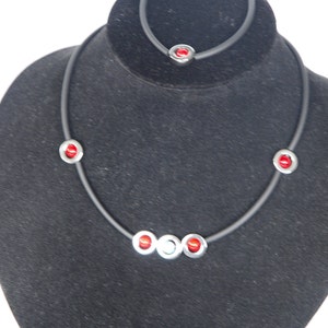 May include: A black necklace with red and silver beads on a black velvet display stand.