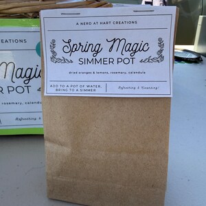 Könnte beinhalten: Ein brauner Papiersack mit der Aufschrift "Spring Magic Simmer Pot". Das Etikett enthält den Text "getrocknete Orangen & Zitronen, Rosmarin, Ringelblume" und die Anweisung "In einen Topf mit Wasser geben, zum Köcheln bringen."