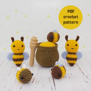 Könnte beinhalten: Häkelanleitung für ein Set aus vier Amigurumi-Bienen. Die Bienen sind gelb und schwarz mit braunen Augen und blauen Flügeln. Das Set enthält einen Honigtopf und einen Honiglöffel.